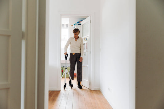 Senior walking assisted with a rollator to move through bedroom doorway into open hallway to show aging in place solutions 